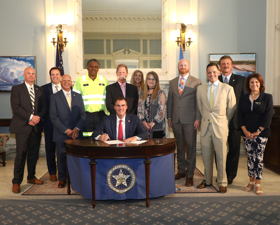 Representatives of law enforcement, state agencies, safety organizations and other officials gathered for a ceremonial signing of Senate Bill 89 by principal Senate author Sen. Brent Howard and principal House author, Rep. Charles Ortega.  Pictured from left to right, Sheridan O/Neal with the Oklahoma Department of Public Safety (DPS), Taylor Henderson, the Oklahoma Department of Transportation (ODOT), Rep. Ortega, Joe Snell, AAA, Roger Straka, ODOT, Leslie Gamble, AAA, Stephanie Richardson, ODOT, Sen. Howard, Sec. of Public Safety, Chip Keating, Sec. of Transportation Tim Gatz, Terri Angier, ODOT and Gov. Kevin Stitt, seated.