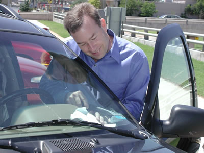 State Senator Jim Reynolds removes a vehicle inspection sticker.