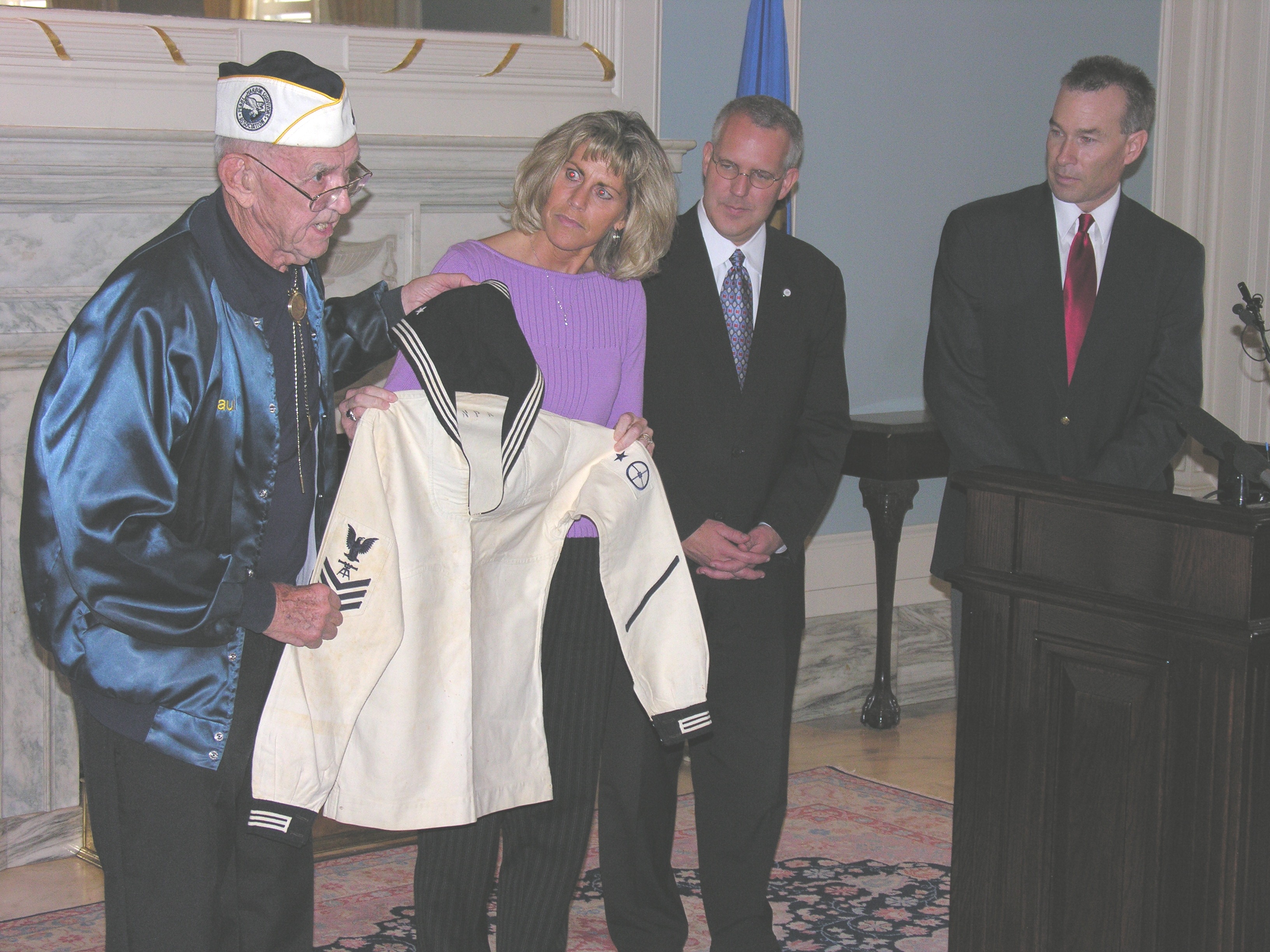 USS Oklahoma survivor Paul Goodyear and Lisa Ridge, granddaughter of Paul Andrews Nash,  display Nash's uniform as Goveror Brad Henry and State Senator Jim Reynolds look on. 