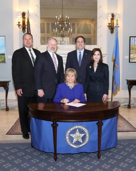   Sen. John Sparks, D-Norman, Bo Rainey, Sen. Kyle Loveless, R-Oklahoma City, and State School Superintendent Joy Hofmeister join Gov. Mary Fallin for the ceremonial signing of Senate Bill 711 in the Blue Room at the State Capitol on Wednesday, June 10.